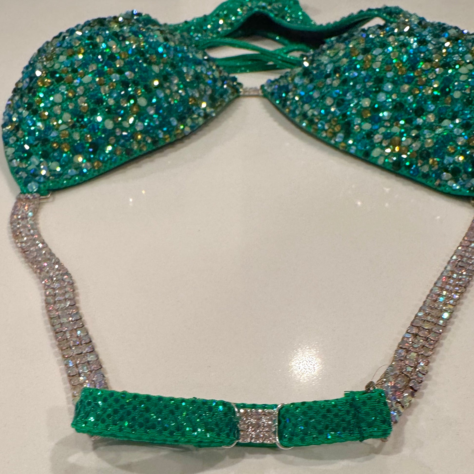 A green figure suit with a holographic base and multicolored stone embellishments, featuring adjustable straps and silver connectors. Denver, Colorado