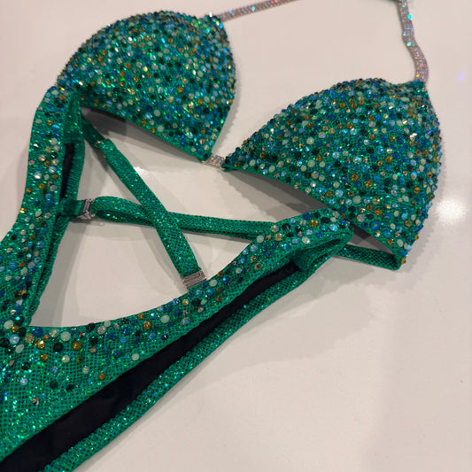 A green glamour suit with a holographic base and multicolored stone embellishments, featuring adjustable straps and silver connectors. Denver, Colorado